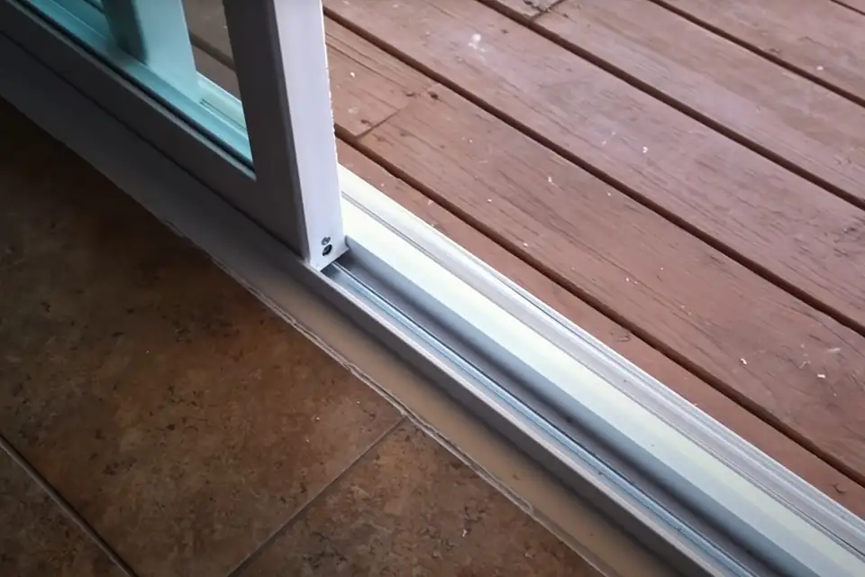 Close-up of a sliding door bottom track and sill where the roller runs